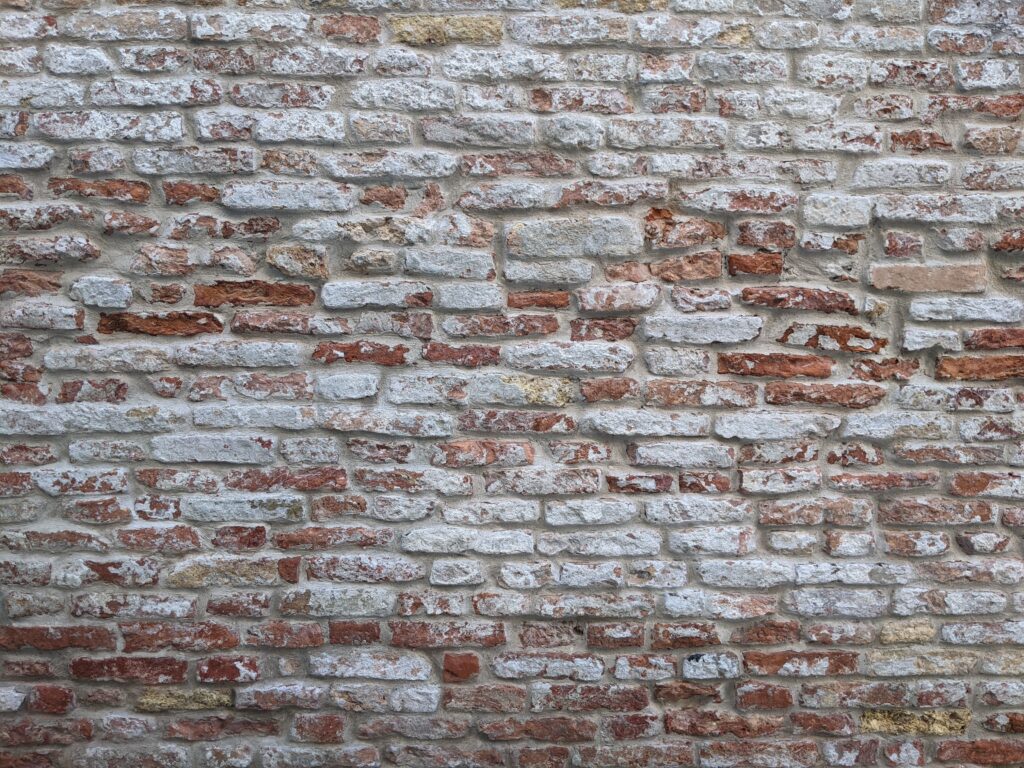 Hydrofugation de façade : ce qu'un couvreur vérifie avant d'appliquer (et quand il refuse) 2 Rustic brick wall texture in Venedig, showcasing weathered surfaces and historic architecture.